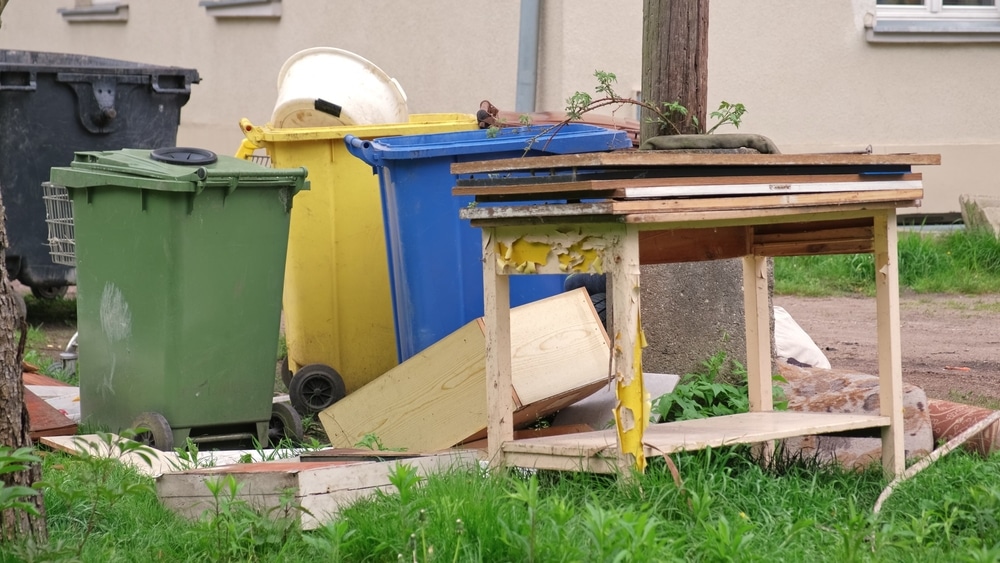 Old Discarded Household Furniture Dumped By Colorful Plastic Dumpsters For