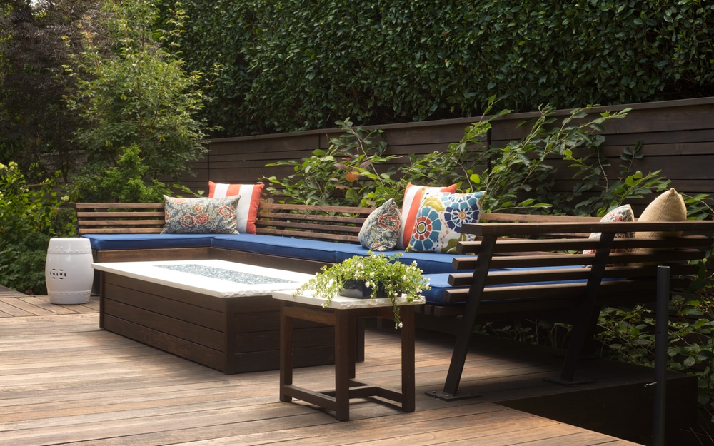 A Contemporary Outdoor Conversation Bench With Pillows On A Wooden