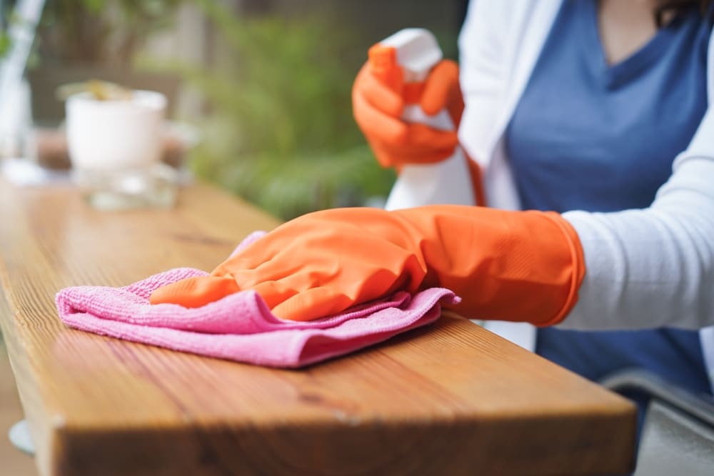 A Woman In Gloves Is Cleaning The Countertop Using A cleaning solution