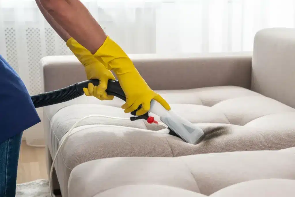 a man cleaning a sofa with a vacuum 